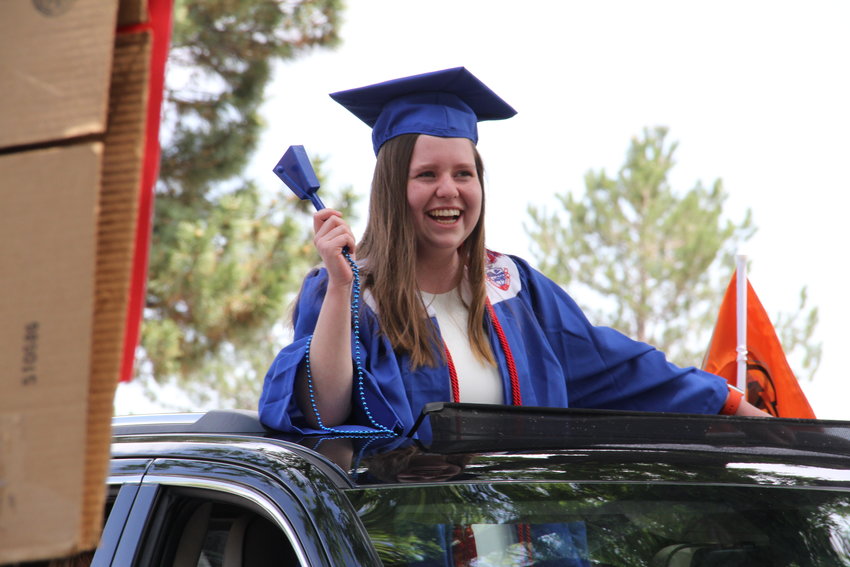 Student Grace Young stands through the open sunroof, wearing her graduation cap and gown during Cherry Creek High's celebration of seniors.
